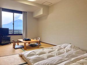 um quarto com uma cama, uma mesa e uma janela em Shoji Mount Hotel em Fujikawaguchiko