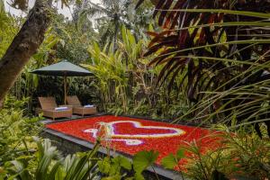 un jardín con una alfombra roja y una fuente de agua en Teja Lokha Ubud Villa, en Ubud