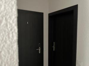 duas portas pretas estão uma ao lado da outra num quarto em Luxuria Modern Apartments - Self Check-in em Šiauliai