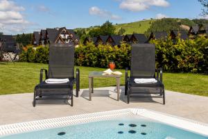 two chairs and a table next to a pool at Hotel Bystra in Białka Tatrzanska