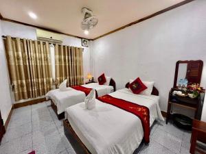 um quarto com duas camas e um espelho em Nocknoy Lanexang Guest House em Luang Prabang