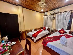 um quarto de hotel com duas camas e uma mesa e uma mesa sidx sidx em Nocknoy Lanexang Guest House em Luang Prabang