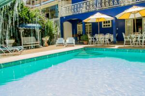 a swimming pool with tables and chairs and umbrellas at Pousada Portal do Mar in Cabo Frio