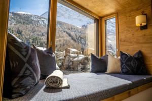 asiento junto a la ventana con vistas a una montaña nevada en Riverside 2nd Floor South, en Saas-Fee