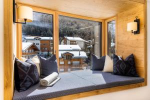 asiento junto a la ventana con vistas a una montaña nevada en Riverside 2nd Floor South, en Saas-Fee