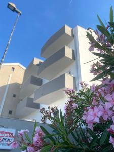 un edificio bianco con fiori viola di fronte di VIESTEROOMS a Vieste