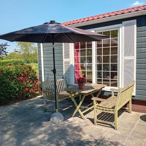 a table and chairs under an umbrella on a patio at Slapen op De Bult Green 2 persons in De Bult