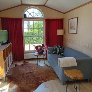 a living room with a blue couch and a window at Slapen op De Bult Green 2 persons in De Bult