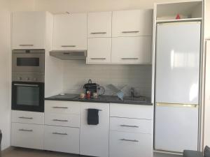 una cucina con armadietti bianchi e frigorifero di Appartement paisible proche centre ville a Bron