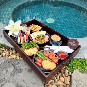 uma bandeja de comida numa mesa ao lado de uma piscina em Cochin Sang Hotel em Cidade de Ho Chi Minh