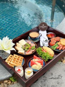 uma bandeja cheia de diferentes tipos de alimentos ao lado de uma piscina em Cochin Sang Hotel em Cidade de Ho Chi Minh