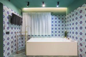 uma banheira na casa de banho com azulejos azuis e brancos em Gioia Home em Pompeia