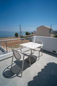 une table blanche et deux chaises sur le toit dans l'établissement Agistri Beach, à Skala