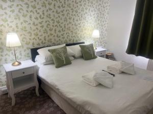 a bedroom with a white bed with two tables and two lamps at Penny Farthing Hotel & Cottages in Lyndhurst