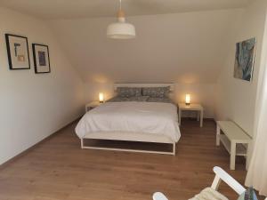 a white bedroom with a bed and two tables at Ferienwohnung Rosi in Schleswig