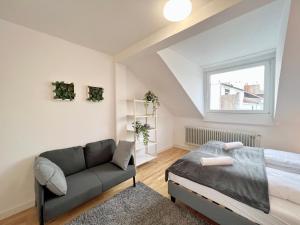 ein Schlafzimmer mit einem Bett, einem Sofa und einem Fenster in der Unterkunft Jungle Retreat Apartments im Zentrum in Bremen