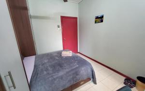 um pequeno quarto com uma cama e uma porta vermelha em Putrajaya Transit Romestay em Putrajaya