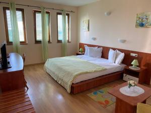 a bedroom with a large bed in a room with windows at Guest House Golden Flake 4km from Bolata beach in Bŭlgarevo