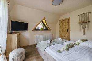 a bedroom with two beds and a tv and a window at Willa Skała in Kościelisko