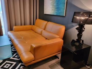 un sofá de cuero marrón en una sala de estar con lámpara en Empire Damansara Designer Soho Karaoke & Netflix, en Petaling Jaya