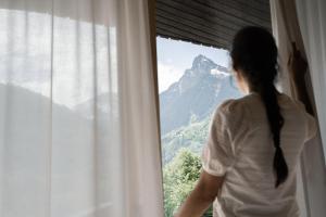 Una mujer mirando por una ventana a una montaña en Amrai Suites, en Schruns