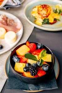 eine Schale Obst auf einem Tisch mit Teller mit Lebensmitteln in der Unterkunft DO & CO Hotel München in München