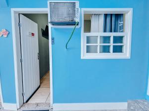 een blauwe kamer met een raam en airconditioning bij Pousada Água Marinha in Cabo Frio