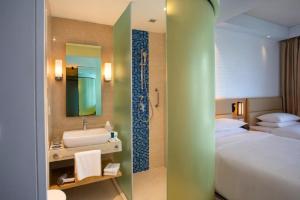 a bathroom with a bed and a sink and a shower at Four Points by Sheraton Chennai OMR in Chennai