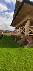 Casa con porche de madera y césped verde en Góralskie Domki na Podhalu - z jacuzzi, en Maniowy