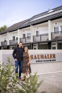 a man and woman standing in front of a building with a dog at zum Sausaler - Boutique Hotel-Pension Südsteiermark in Sankt Nikolai im Sausal