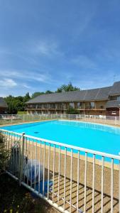 una gran piscina azul detrás de una valla en L’entrelacs, en Équemauville