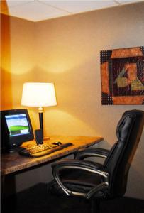 einen Schreibtisch mit einem Computer, einer Lampe und 2 Stühlen in der Unterkunft Ramada by Wyndham Bettendorf in Bettendorf