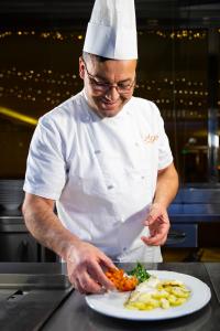 een chef-kok die een bord met eten bereidt in een keuken bij Hotel Residence Federiciano in Valenzano