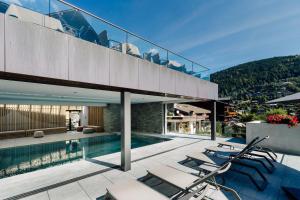 una casa con piscina y algunas sillas en Hôtel Champs Fleuris Morzine, en Morzine