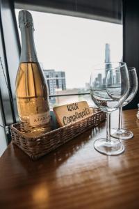 a bottle of champagne and two wine glasses on a table at ‘Sunrise on Aura’ Apartment with stunning views. in Melbourne