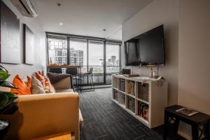 a living room with a couch and a flat screen tv at ‘Sunrise on Aura’ Apartment with stunning views. in Melbourne