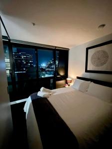 a bedroom with a large bed with a view of a city at ‘Sunrise on Aura’ Apartment with stunning views. in Melbourne