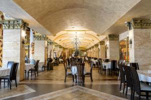 a dining room with tables and chairs and a chandelier at Imperial Palace Hotel in Sunny Beach