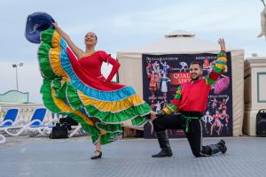 a man and a woman in a colorful dress dancing at Imperial Palace Hotel in Sunny Beach