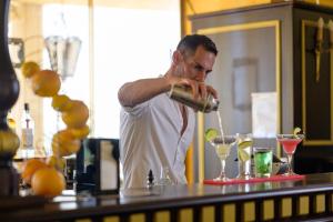 a man standing at a bar making a drink at Imperial Palace Hotel in Sunny Beach