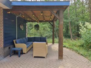 eine Pergola mit einem Sofa und Stühlen auf einer Terrasse in der Unterkunft Holiday home bos en heide in Otterlo