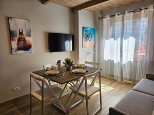 uma sala de jantar com uma mesa com cadeiras e uma televisão em Moda Apartments 69 em Sestriere