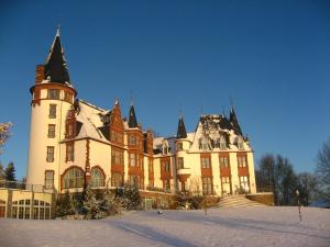 un grande edificio con neve sul terreno di Seehotel Schloss Klink a Klink