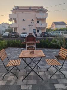 uma mesa de piquenique e duas cadeiras em frente a um edifício em Apartman Mila em Biograd na Moru