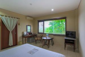 - une chambre avec un lit, un bureau et une fenêtre dans l'établissement The Jayakarta Suites Komodo Flores, à Labuan Bajo