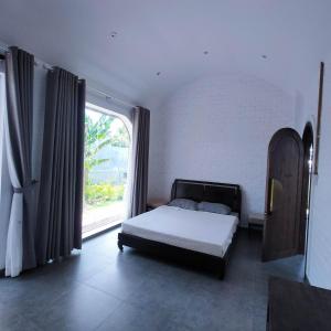 GOLDEN LOTUS SPA & HOMESTAY في Ấp Thiện Phước: غرفة نوم بسرير ونافذة كبيرة