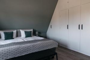 a bedroom with a bed with white cabinets and green pillows at Schlei Hotel in Kappeln