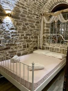 a bed in a room with a brick wall at Cozy stone built apartment in Nénita! in Chios