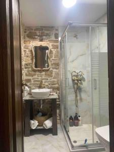 a bathroom with a glass shower and a sink at Cozy stone built apartment in Nénita! in Chios