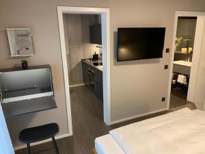 pokój hotelowy z telewizorem na ścianie i łóżkiem w obiekcie Timehouse Serviced Apartments w Monachium